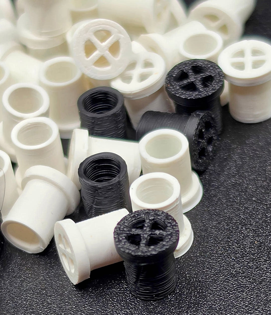 Vent plugs close up, black ridged ones in front, each face divided into four by a raised cross.