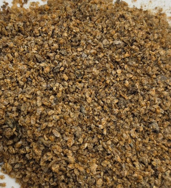 Dried daphnia filling almost the whole frame, tightly packed light and dark brown flakes.