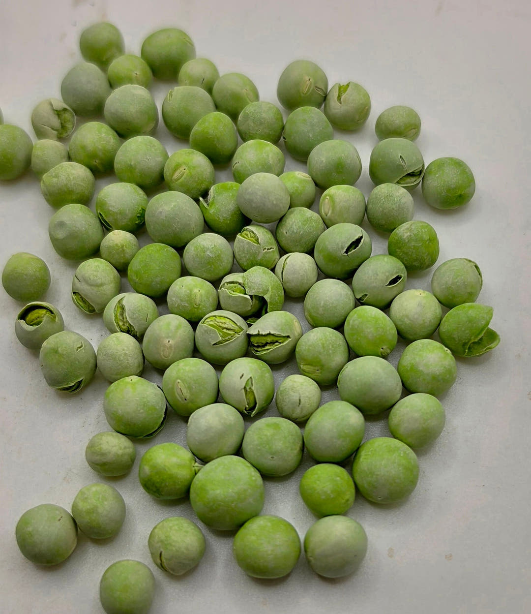A dense spread of freeze-dried garden peas filling the frame, several of them split open along one side.