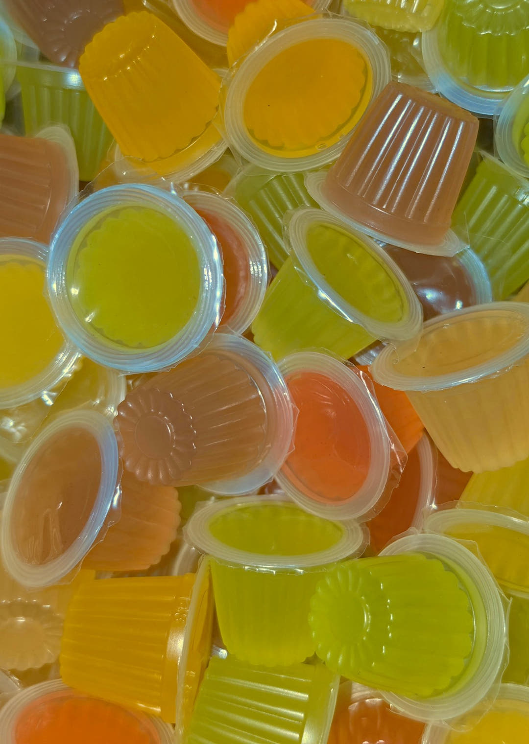 Mixed jelly pots piled up, one at the centre showing the daisy pattern moulded into its base.