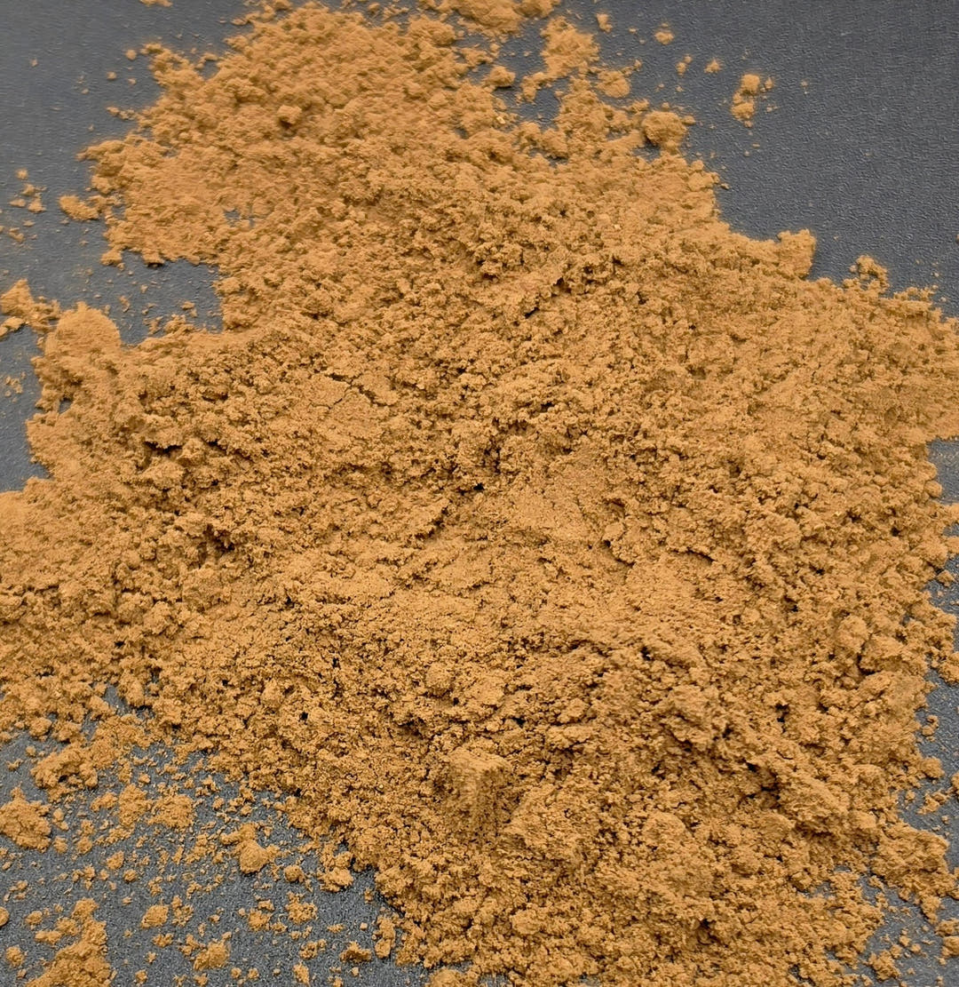 A loose spread of tan mushroom blend powder scattered across a dark grey surface.