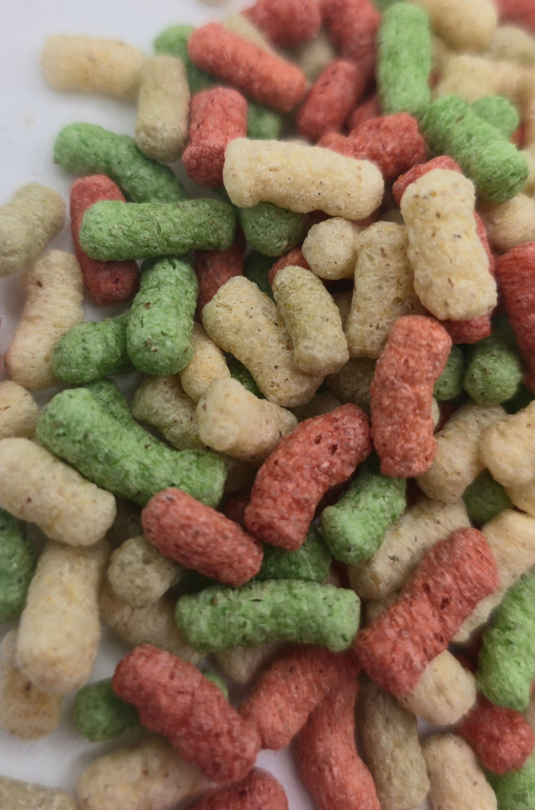 Pond sticks in red, green and cream spread over a white surface, each one short and porous.