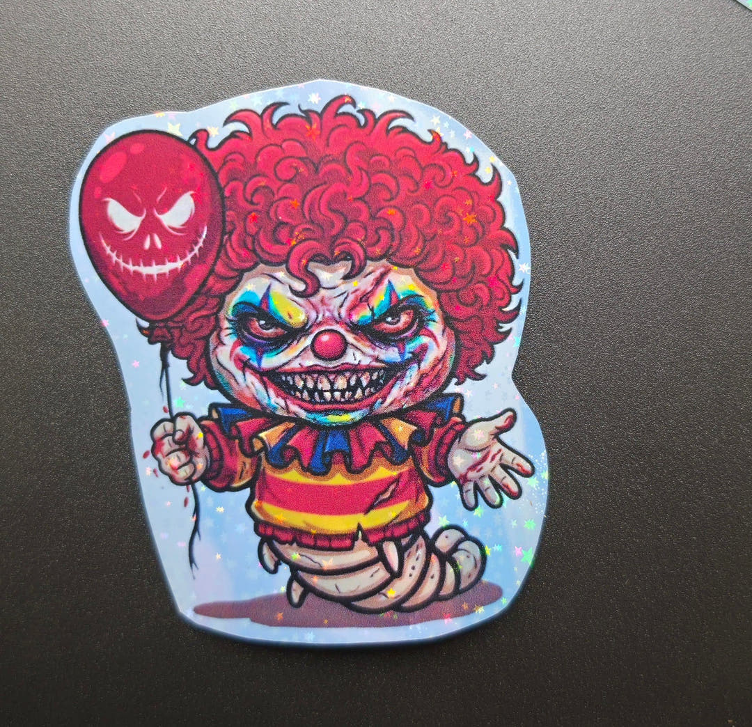 A glittery sticker of a grinning clown holding a red balloon, its body ending in a segmented isopod tail.