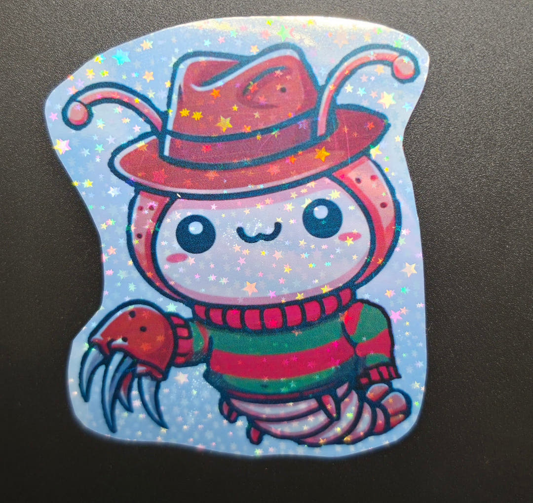 A glittery sticker of an isopod in a red fedora and red and green striped jumper with a clawed glove.