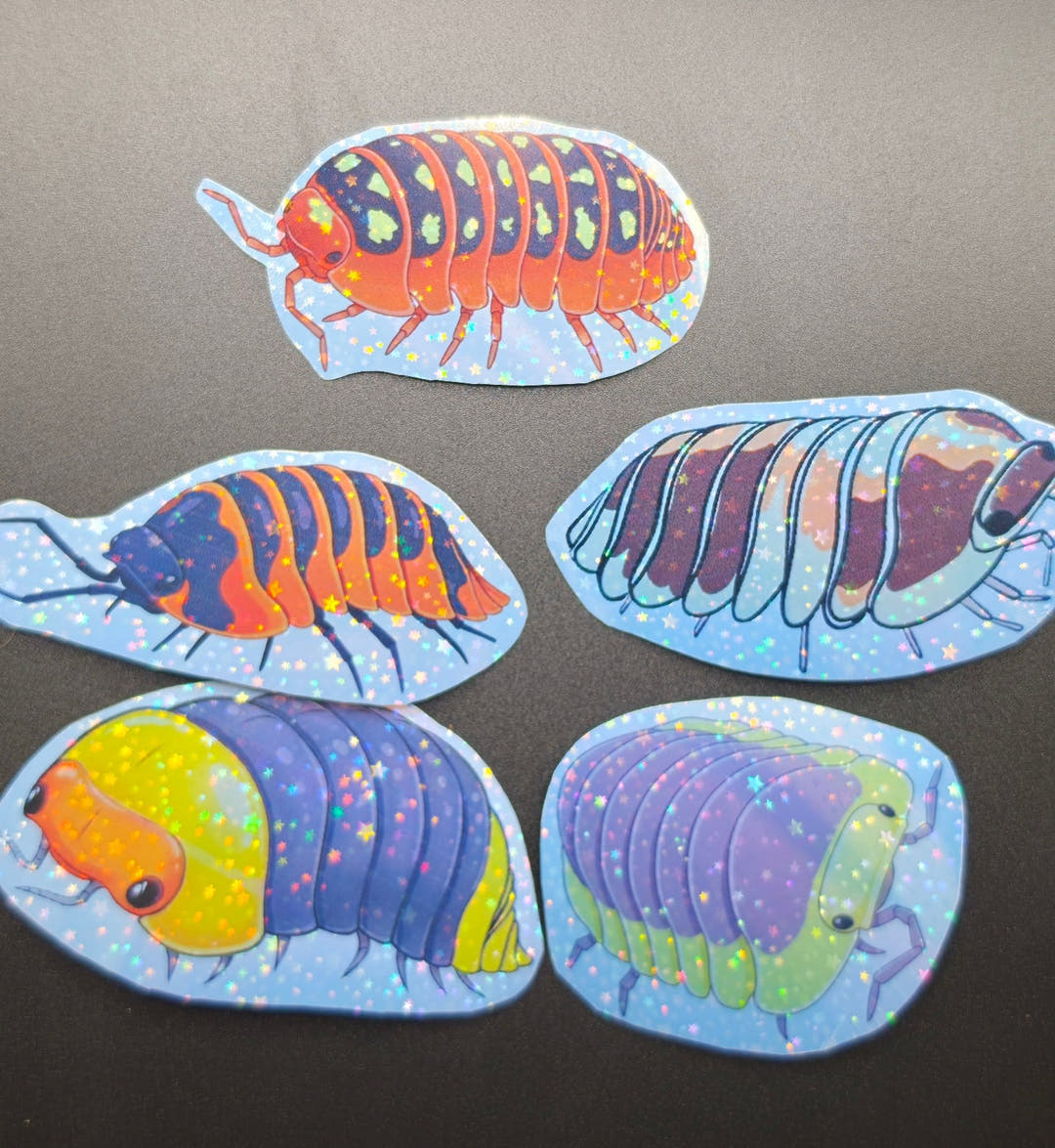Five holographic vinyl stickers on a dark surface, each showing a cartoon isopod in different colours.