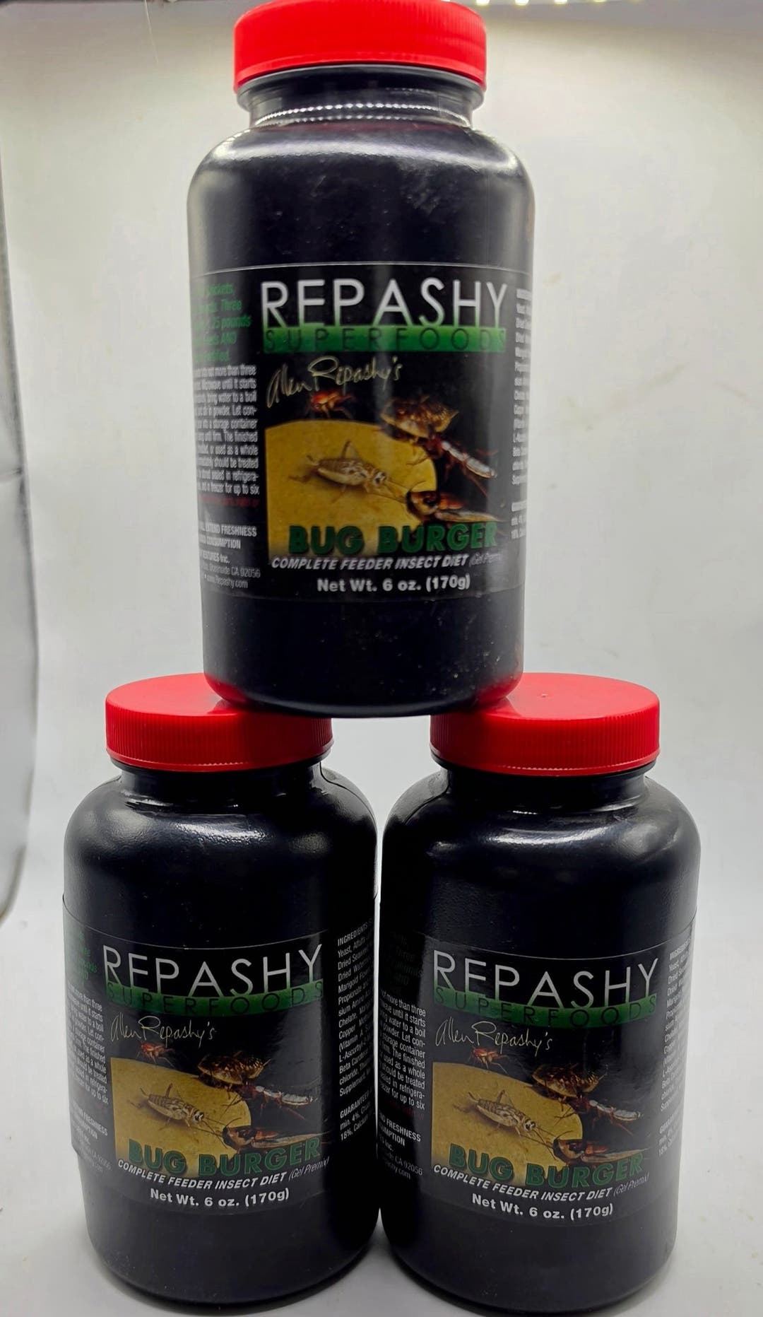 Three black Repashy Bug Burger jars with red lids stacked in a pyramid, each labelled 6 oz 170g.