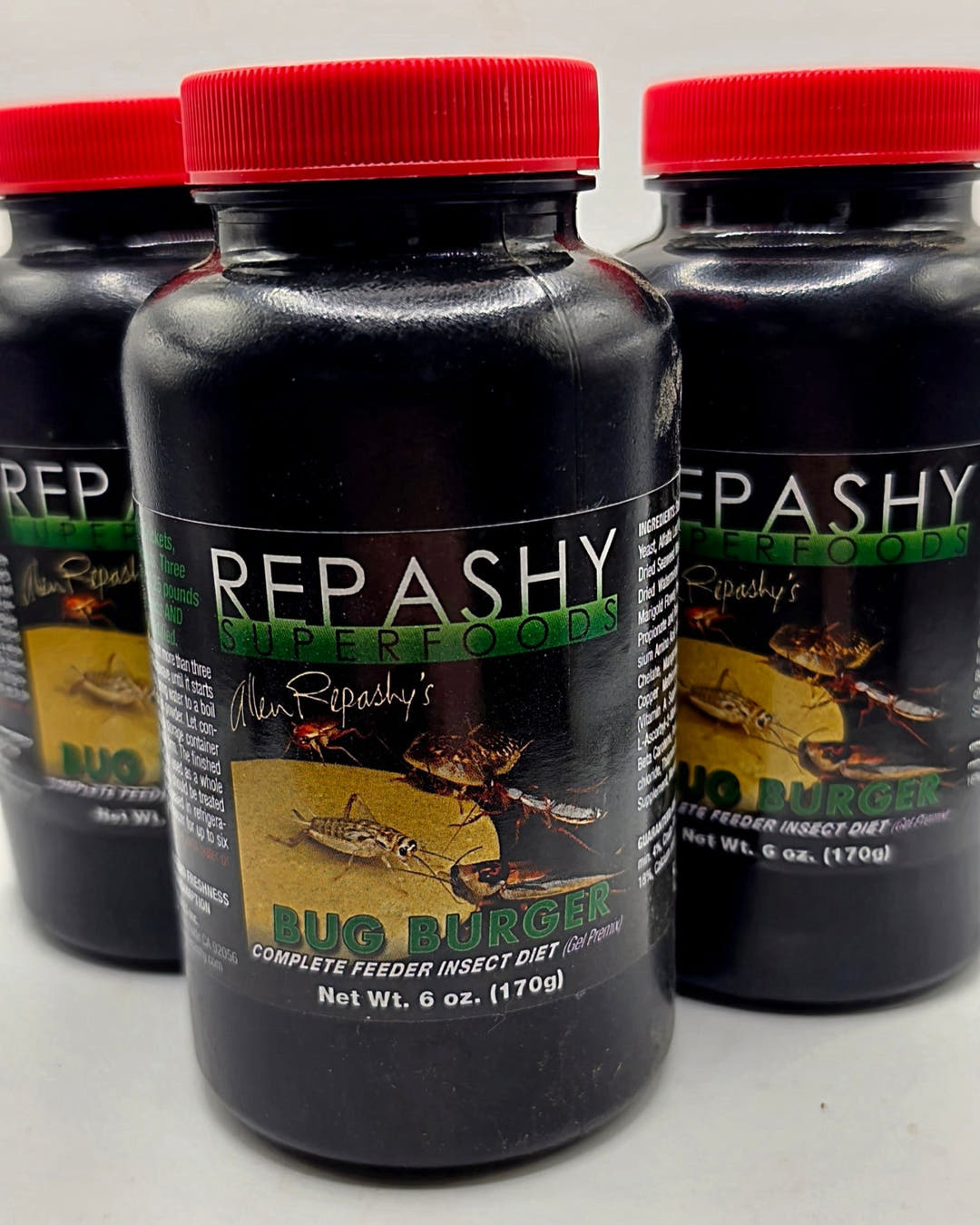 Three 6 oz 170g Repashy Bug Burger jars in a row, the middle one sharp and the other two behind it.