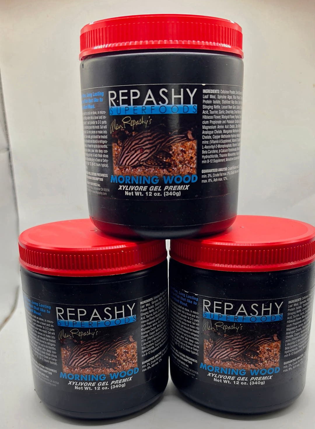 Three black Repashy Morning Wood tubs with red lids stacked in a pyramid, each marked Net Wt. 12 oz (340g).