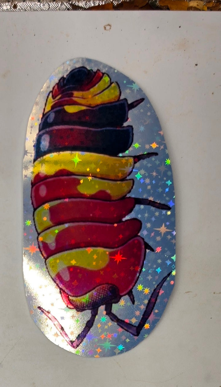 Scarlet isopod sticker: a curled crimson isopod splashed with yellow and banded with deep navy, on holographic star vinyl.