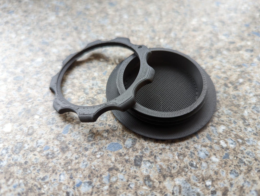 A screw-in air vent shown with its locking ring separated, on a worktop.