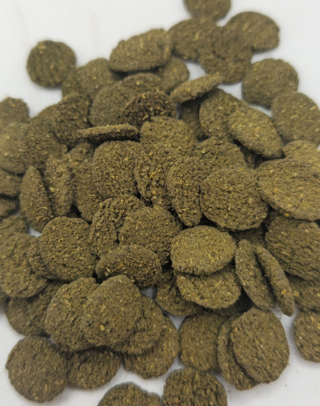 Olive-brown algae wafers packed closely together, their flecked pressed texture visible.